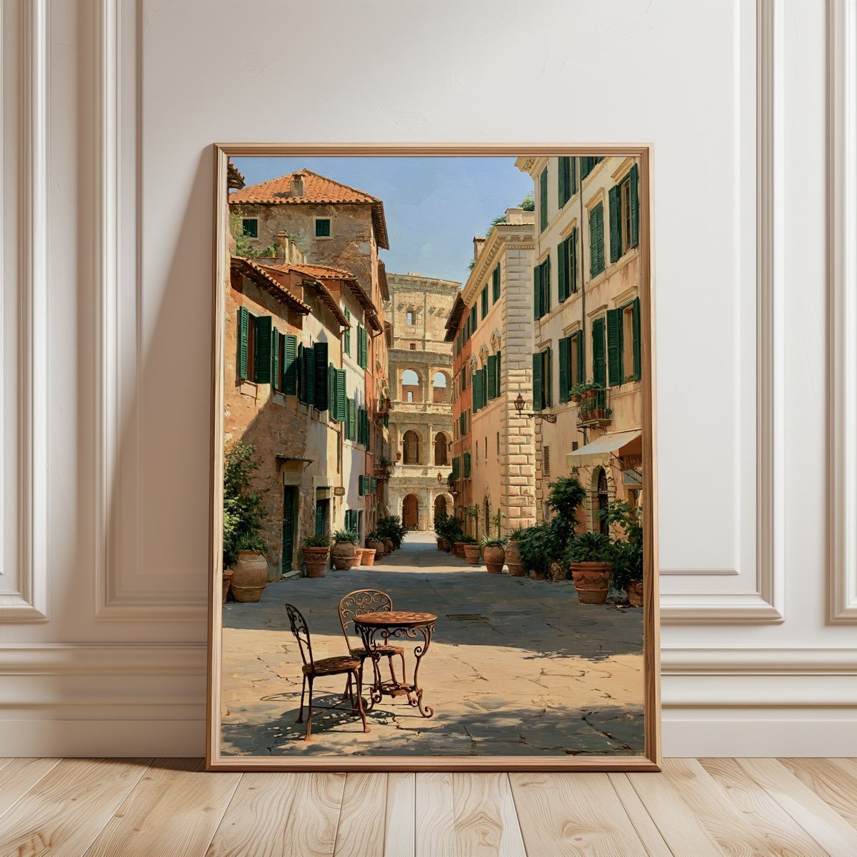 Framed print of a sunlit Roman piazza with cafe chairs, leaning against a white panelled wall on a wooden floor.