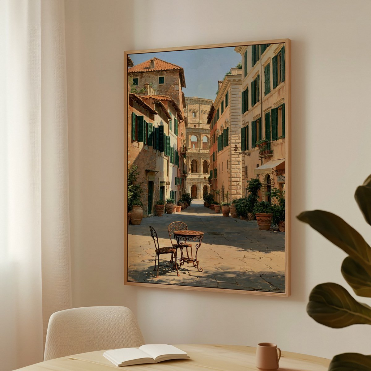 The same framed print hanging above a desk, with an open book, a mug and a plant in soft window light.